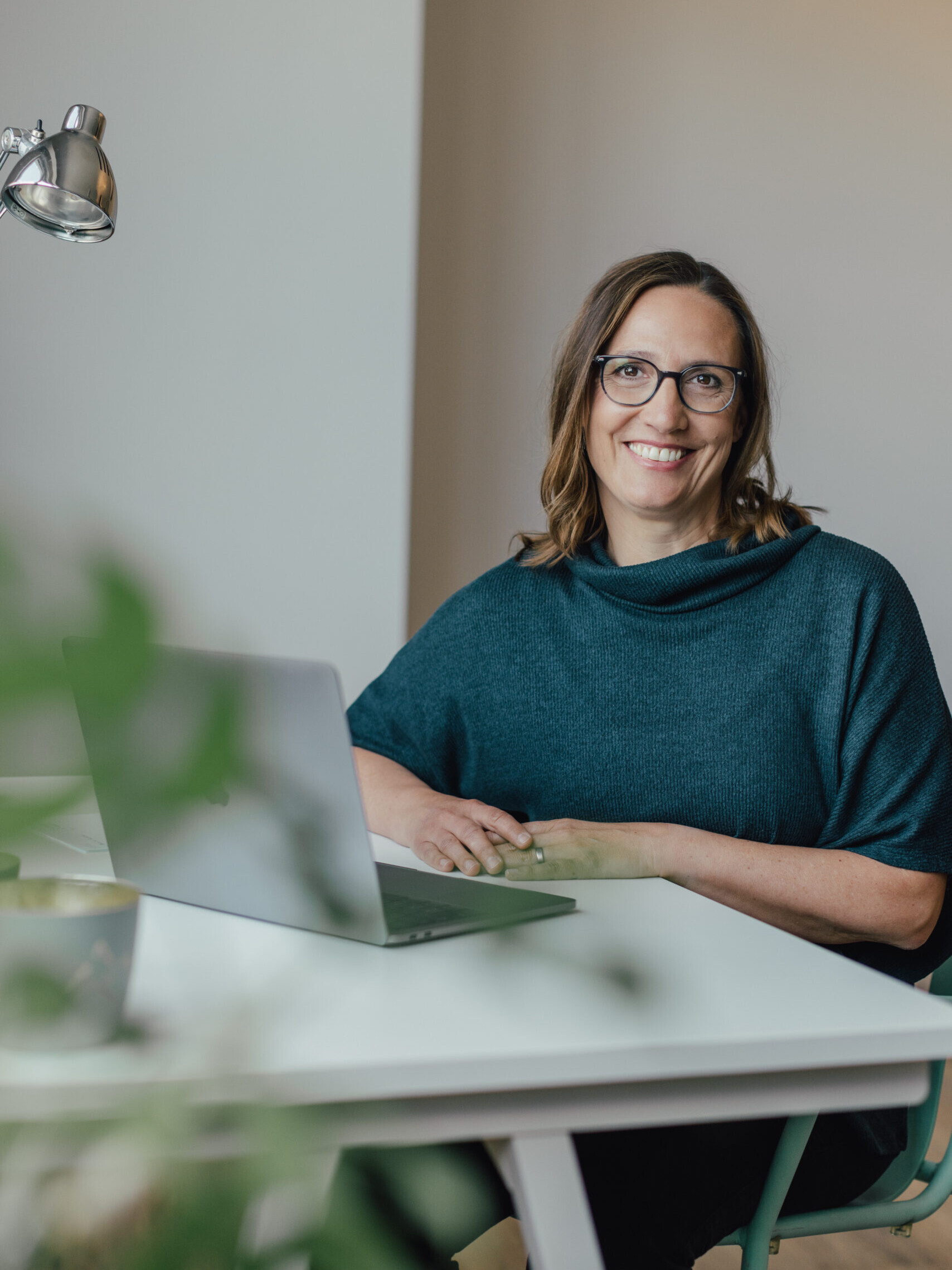 Führungskräftecoach Christiane Kaiser arbeitet lächelnd am Laptob