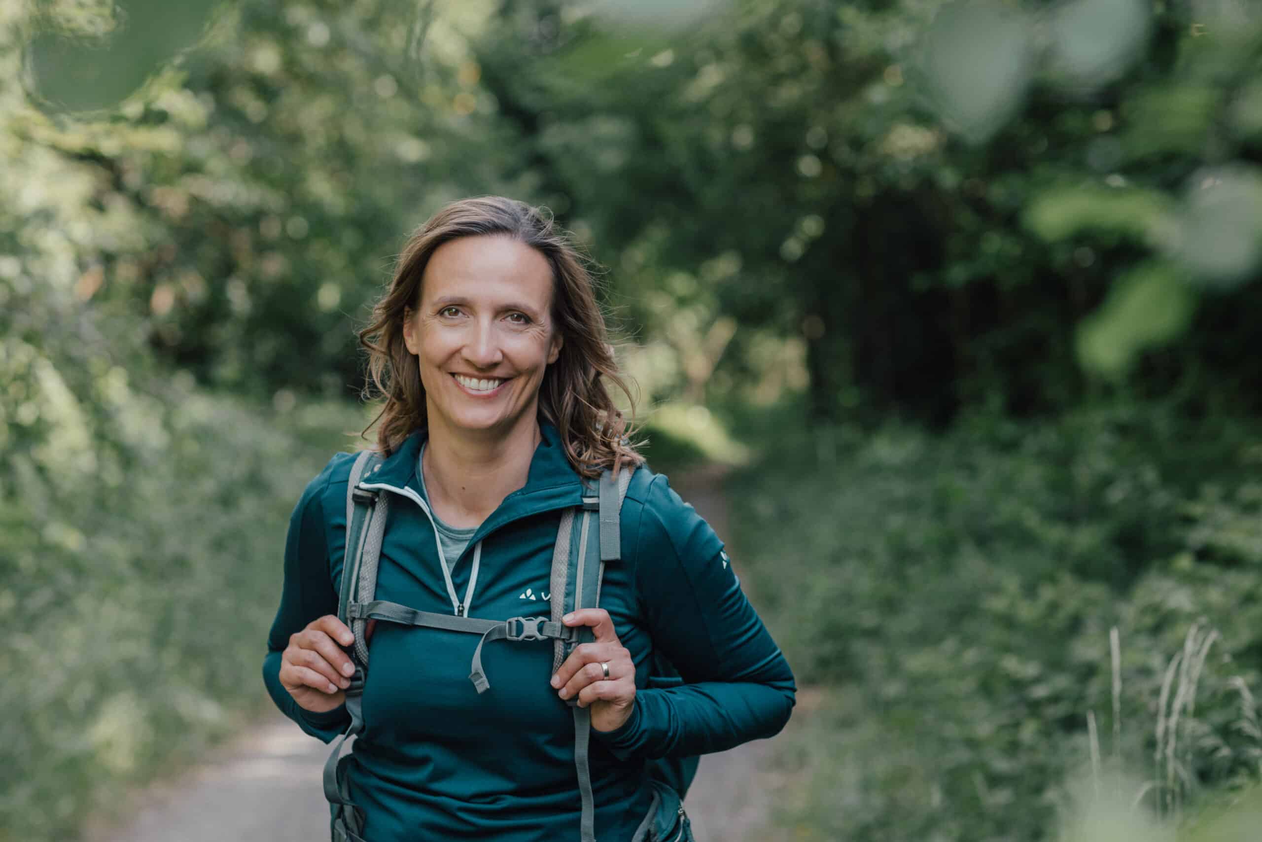 Unternehmer-Coach Christiane Kaiser lächelt beim Wandern in die Kamera