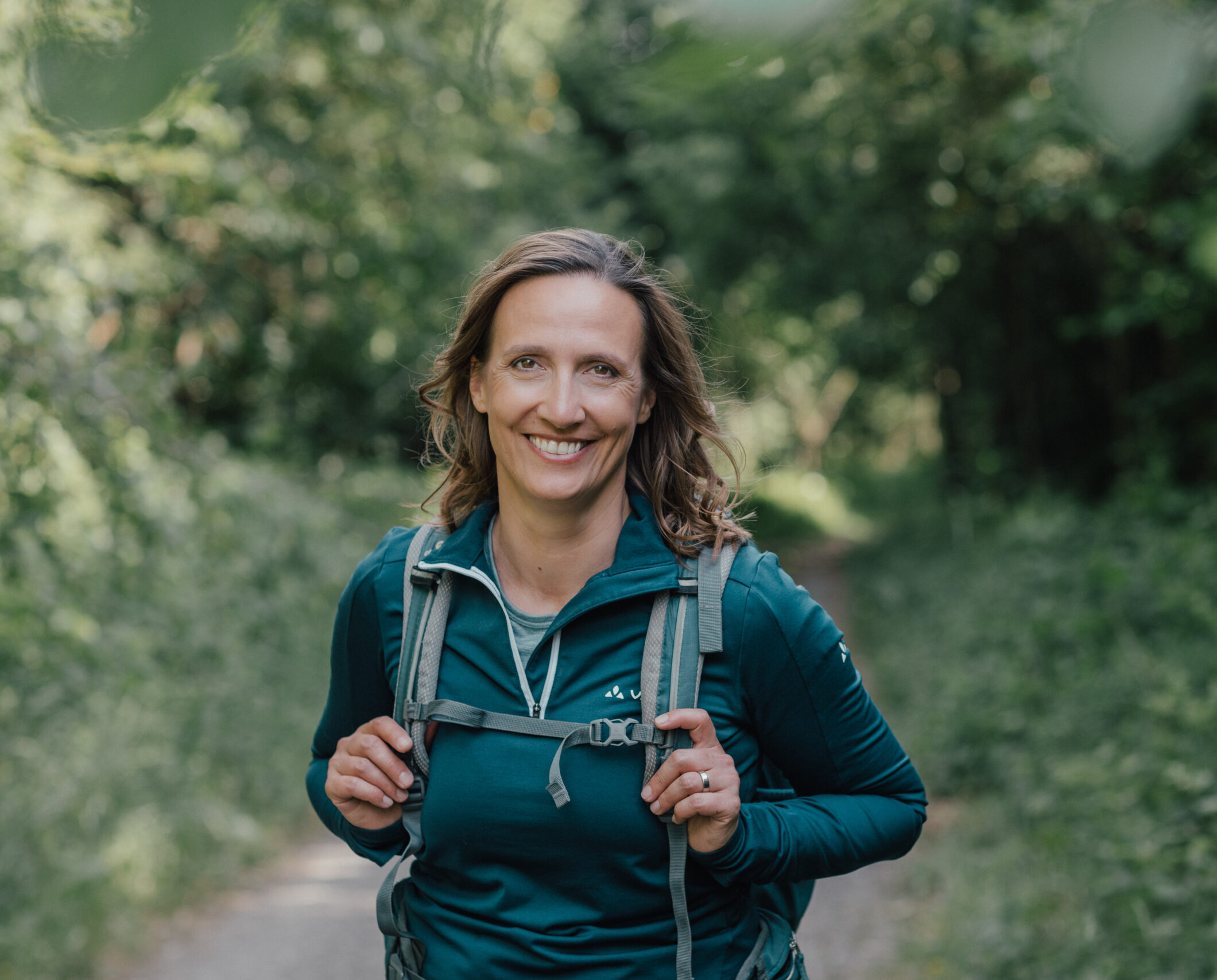 Naturcoach Christiane Kaiser schaut beim Wandern lächelnd in die Kamera