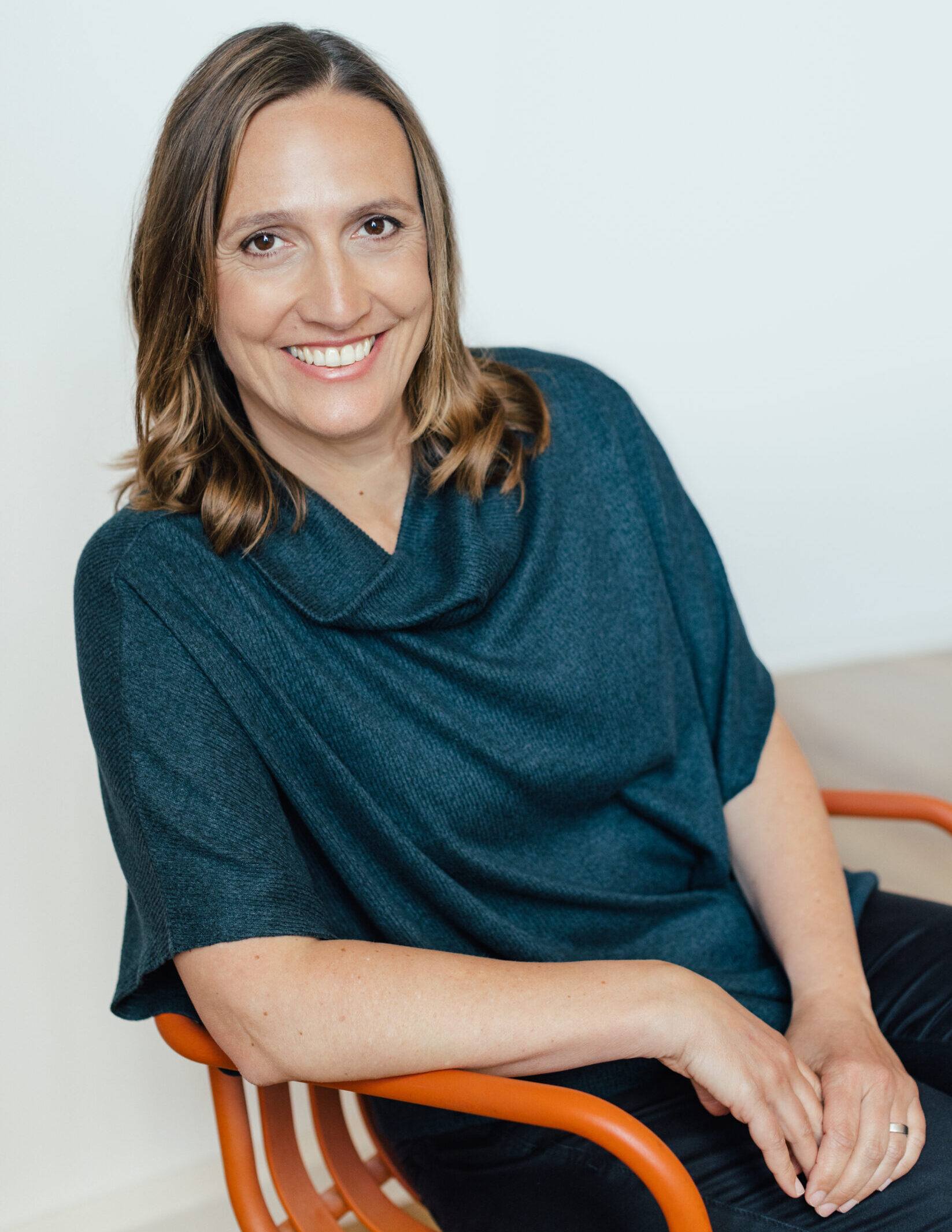 Coach Christiane Kaiser sitzt entspannt und lächelnd auf einem Stuhl