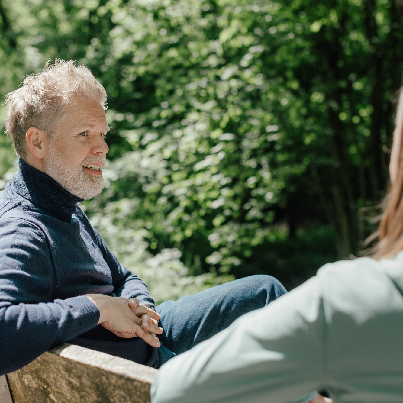 Coach Christiane Kaiser sitzt mit einem Klienten bei einem Coachingespräch auf einer Bank in der Natur