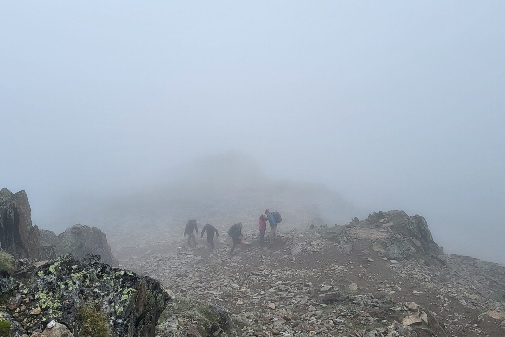 Christiane Kaiser steigt mit Familie bei dichtem Nebel über ein steiniges Bergmassiv auf einen im Nebel verschwindenden Gipfel